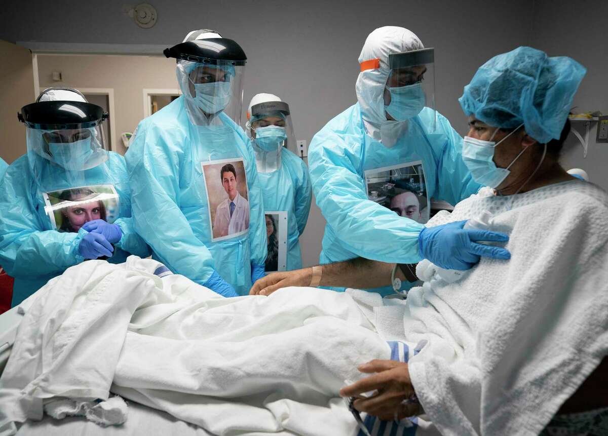 Juan Carlos Peña, 43, is checked on by physicians and nurses before administering an ultrasound on his lungs at UMMC's COVID-19 intensive care unit Tuesday, April 28, 2020, in Houston. Peña decided to go to the hospital after spending a week with a fever, body ache, and nonstop coughing.