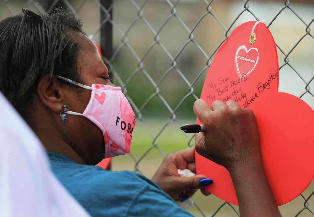 Audrey Wagstaff writes a note to honor her son, Robert, who died from COVID-19, during a memorial at Hemisfair in May. The event honored more than 3,400 people who died from the virus. The number of coronavirus cases is on the rise again in San Antonio.