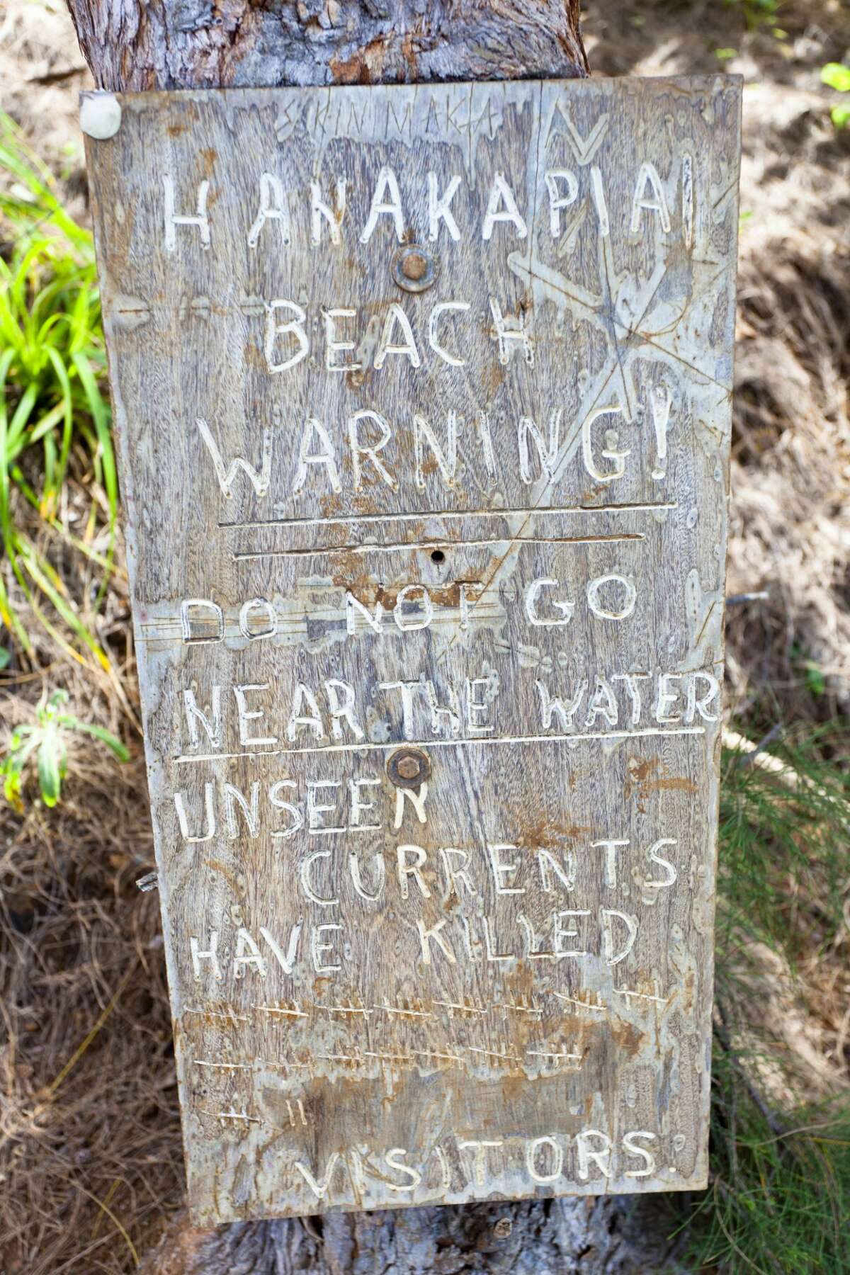 An infamous, and unofficial, sign before Hanakapi‘ai Beach in Kauai warns visitors of its dangers. The bay has a unique geology and is considered one of the most dangerous beaches in the world because of currents and monster waves.