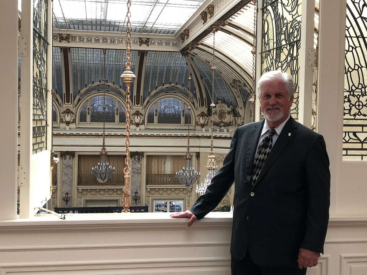 Clifton Clark, general manager of the Palace Hotel, is overseeing the reopening of the historic facility, including the elegant Garden Court, shown behind him.
