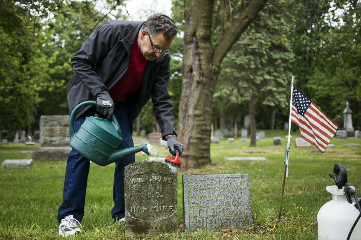 Floyd Andrick of the Midland County Historical Society begins the process of cleaning the headstone of civil war veteran William H. Hurd Thursday, May 27, 2021 in the Midland Municipal Cemetery. The headstone on the left was previously cleaned by Andrick. (Katy Kildee/kkildee@mdn.net)