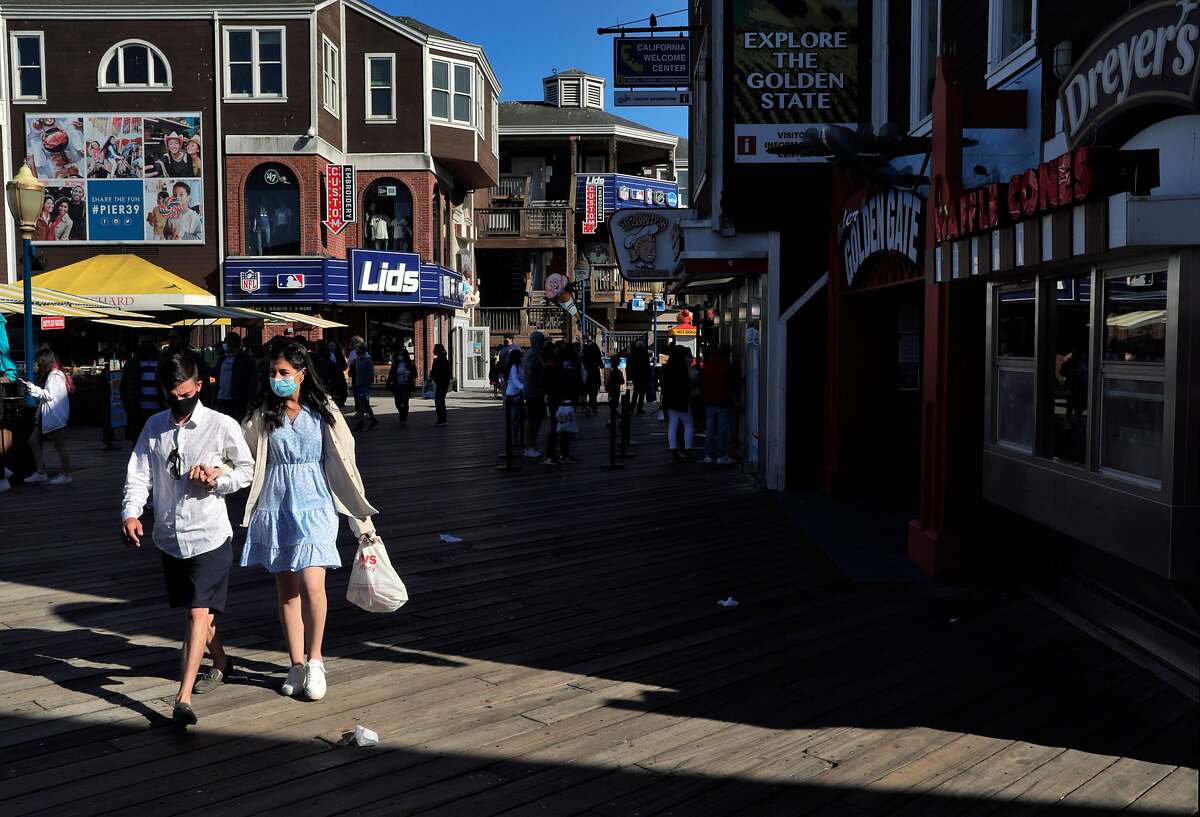 Ryan Berg and Maggie Levangie, of Boston, walk along Pier 39 while on vacation in San Francisco, Calif., on Monday, May 24, 2021. Tourism has begun to pick up again in San Francisco in advance of the travel season as the city’s reopening has offered people the chance to visit with little fear of infection of COVID-19.