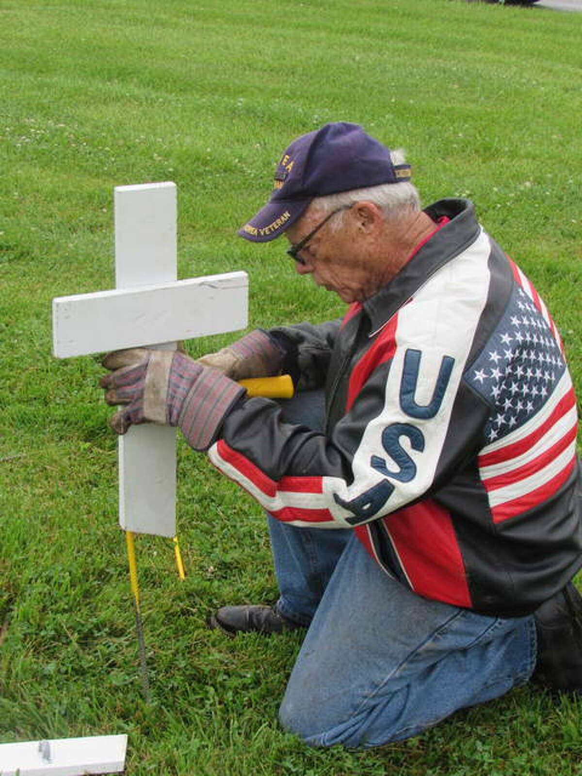 Fred Smith of Alton places miniture crosses at a Memorial Day display in Alton. He also created displays in Grafton and Bethalto.