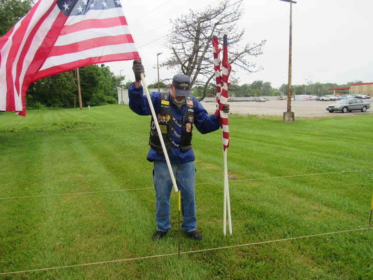 Bob Hillen sets flags in place Friday morning outside Farm & Home on Homer M. Adams Parkway in Alton.