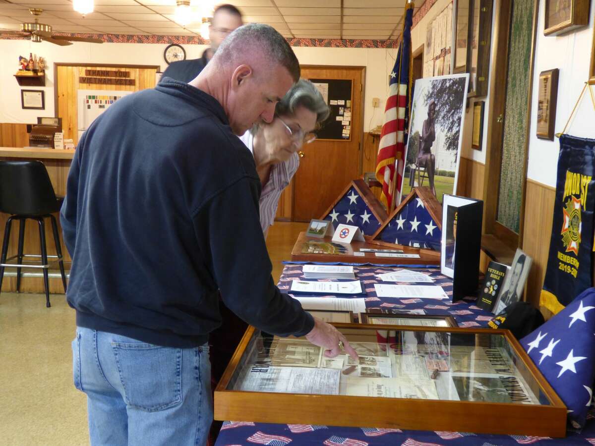 Marla Sexton presents Kaleva VFW post commander Sean Knudsen with a shadowbox memorial containing items from her late husband's service with the U.S. Armed Forces.