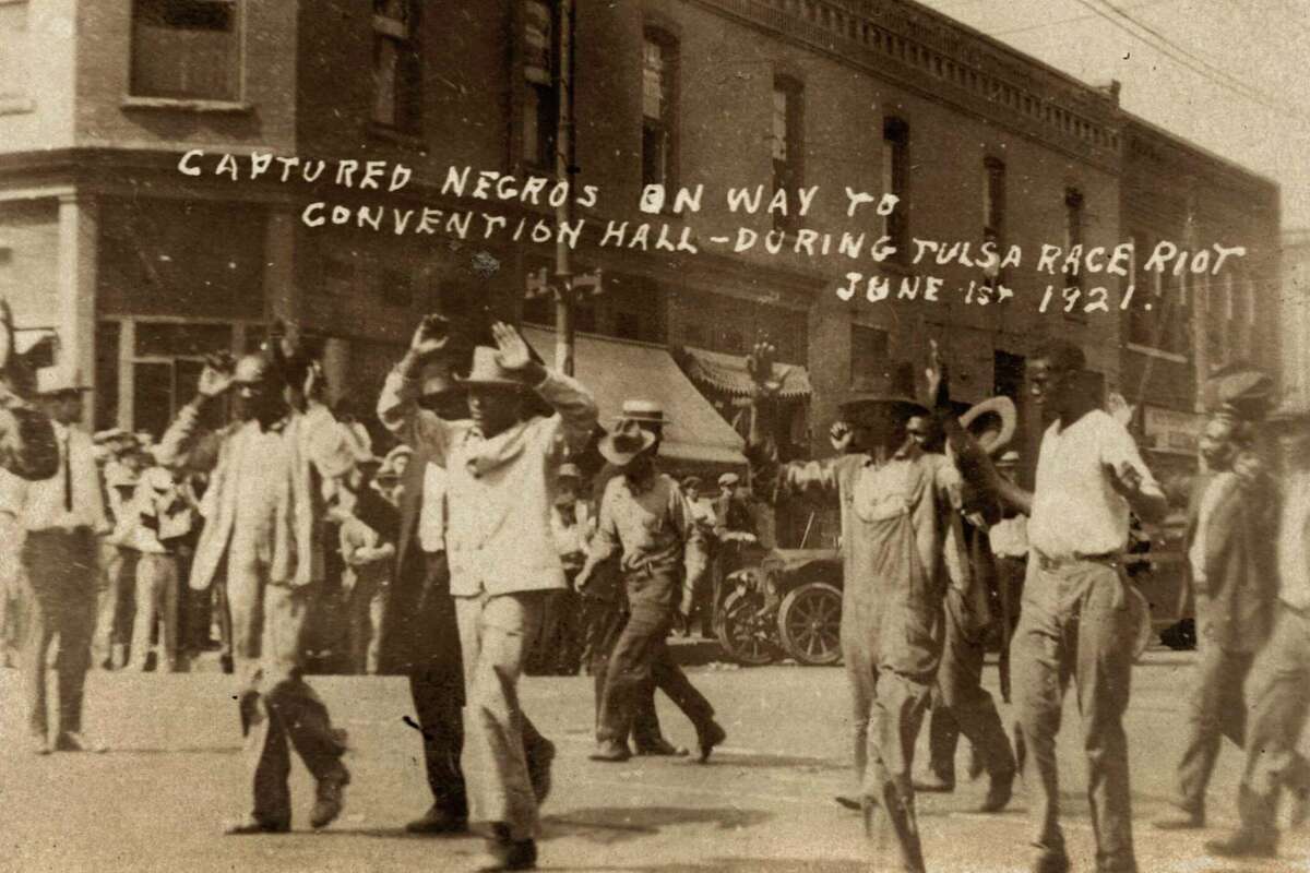 In this photo provided by the Department of Special Collections, McFarlin Library, The University of Tulsa, a group of Black men are marched past the corner of 2nd and Main Streets in Tulsa, Okla., under armed guard during the Tulsa Race Massacre on June 1, 1921. On May 31, 1921, carloads of Black residents, some of them armed, rushed to the sheriff's office downtown to confront whites who were gathering apparently to abduct and lynch a Black prisoner in the jail. Gunfire broke out, and over the next 24 hours, a white mob inflamed by rumors of a Black insurrection stormed the Greenwood district and burned it, destroying all 35 square blocks. Estimates of those killed ranged from 50 to 300. (Department of Special Collections, McFarlin Library, The University of Tulsa via AP)