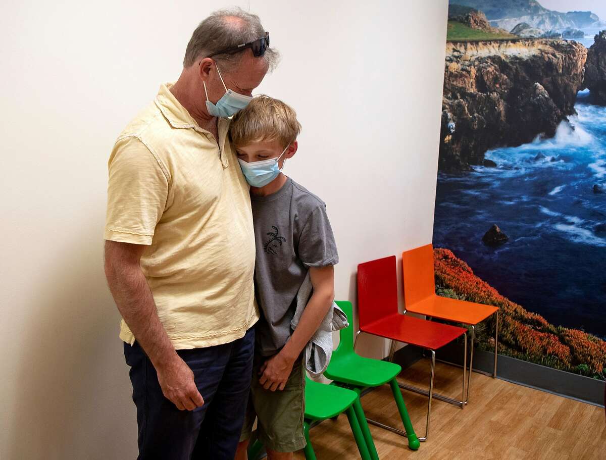 Ryan Youngberg, 12, embraces his father Kris Youngberg after receiving a dose of a Covid-19 vaccine at Tamalpais Pediatrics in Larkspur, California on May 26, 2021.