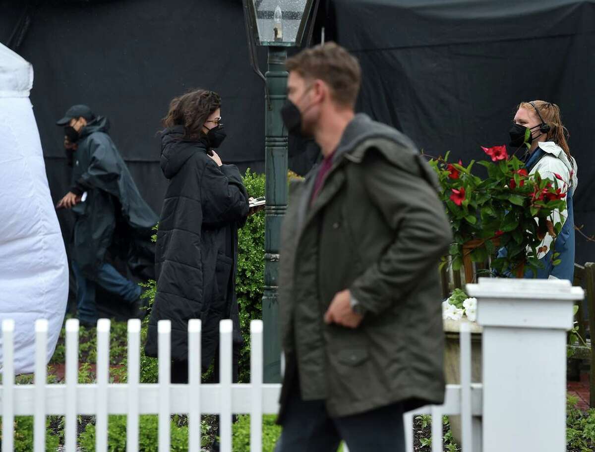 Actors Justin Hartley (right center) walks between locations on the Griswold Inn property during the filming of scenes for the Netflix movie, based on 