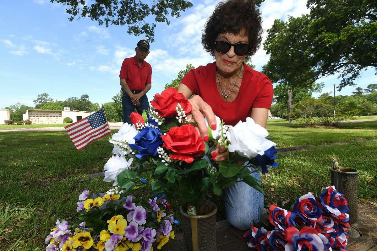 Kaye Bryant places patriotic themed flowers at the graves of her mother Belle and father A.B. Ener, a WWII veteran, as her husband George, a Korean War veteran, looks on at Forest Lawn Memorial Park Sunday in preparation for Memorial Day. The Bryant's then moved on to her aunt and uncle and uncle's brother's graves. Mae, Pat and Bryant Barry all served in the military during WWII. Bryant's aunt was her mother's identical twin, and their families were so close Faye recalls that she and George named their son Barry in their honor - ironically making him Barry Bryant, a mirror image of her uncle Pat's brother - Bryant Barry. Photo made Sunday, May 30, 2021 Kim Brent/The Enterprise