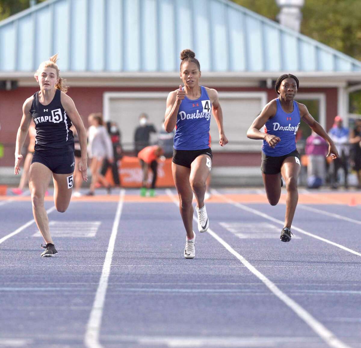 Danbury's Alanna Smith, (lane 4) finished first in the 100 meter dash). Wilton's Staples Francine Stevens, left, and Danbury's Florence Dickson, right, follow. FCIAC girls tack championships at Danbury High School, Monday afternoon, May 24, 2021, in Danbury, Conn.
