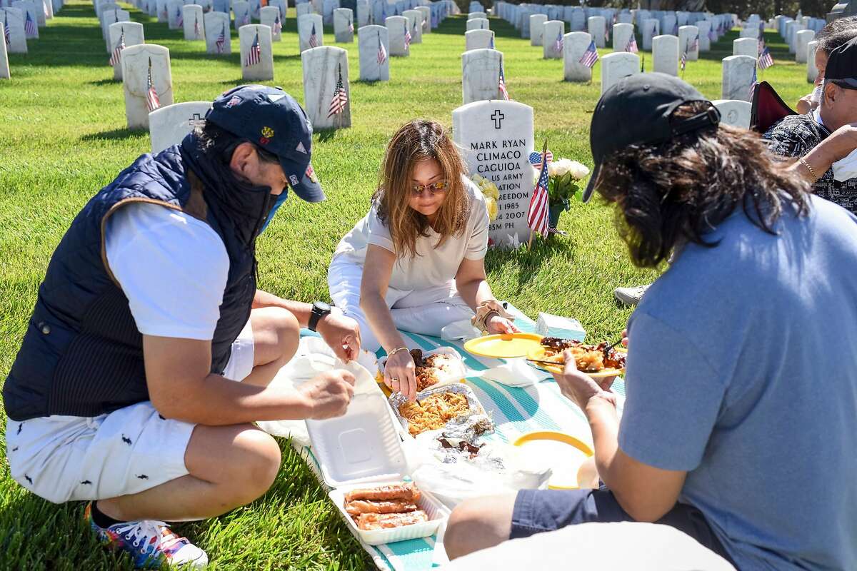 Bing Chacker, left, Maria Lourdes Millare, her husband, Gilbert Millare, and Maria’s parents, Arthur Climaco and Teresita Climaco, set up a picnic next to the grave of Mark Ryan Climaco Caguioa, the son of Maria and Gilbert, at San Francisco National Cemetery in San Francisco, Calif. on Memorial Day, Monday, May 31, 2021. Mark died on May 24, 2007 from injuries while serving in Bhagdad, Iraq, at the age of 21. Maria said the family came to honor not only her son, “but also the other service men and women.”