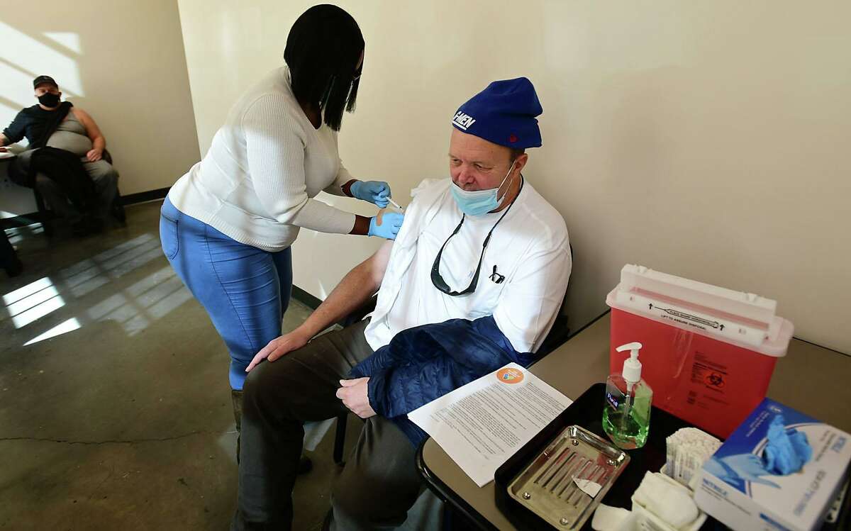 Open Door homeless shelter client Ted Bancroft receivs the injeection as the shelter administers its first corona virud vaccines for residents and staff by Norwalk Community Healthcare Center nurse Yolanda Taylor Friday, February 12, 2021, at the Smiloe Lice Center in Norwalk, Conn.