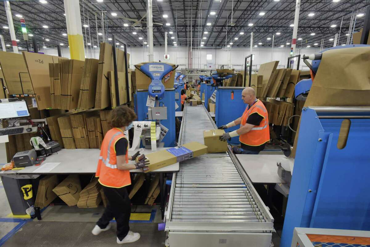 Employees work boxing up items for customers at the Amazon fulfillment center on Wednesday, June 2, 2021, in Schodack, N.Y. Computers inform workers which box to use for an item and a computer figures out the correct amount of tape needed to close the box. From the fulfillment center packages are sent to an Amazon sortation center or a delivery station. (Paul Buckowski/Times Union)
