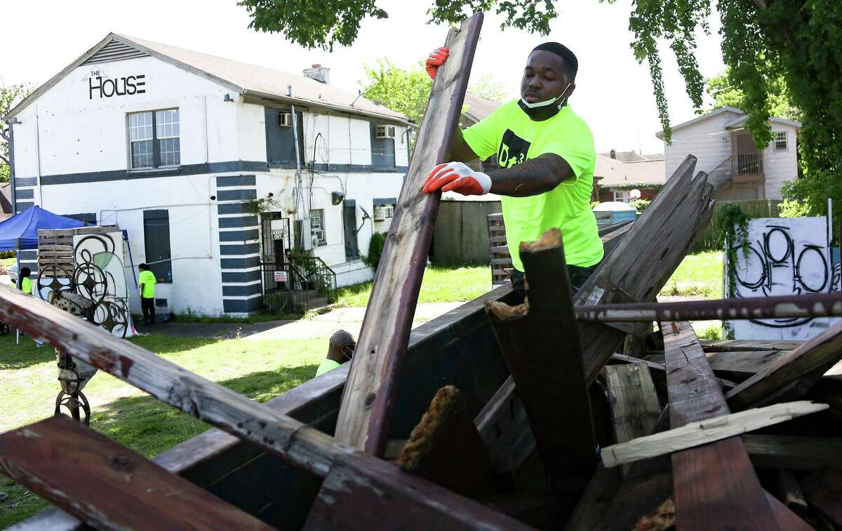 Volunteer Justin Taylor works on filing a trash container on property purchased by Third Ward Real Estate Council in Houston on Saturday, April 24, 2021.