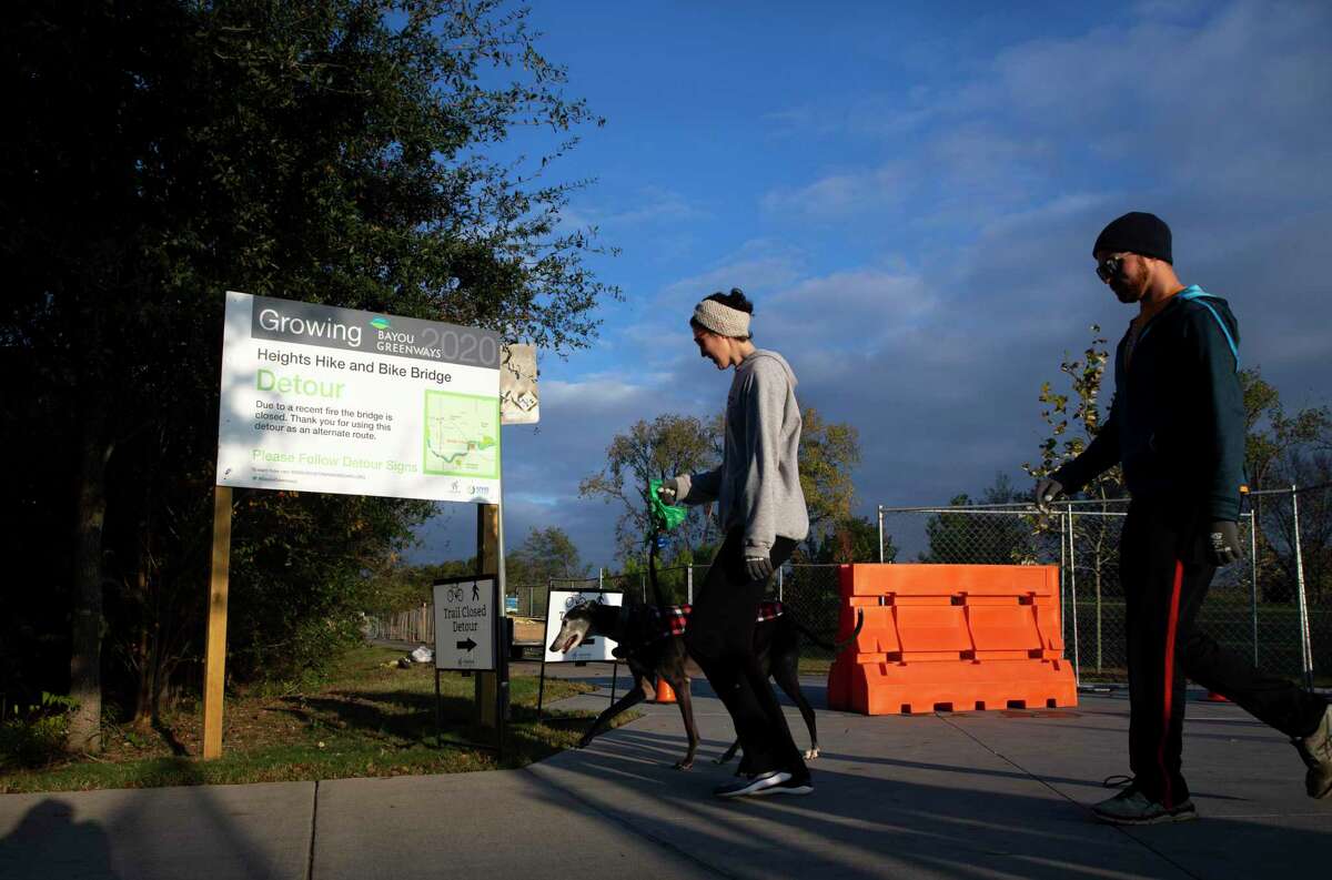 Rebekah Taylor and Justin Lehr make a detour to White Oak Bayou Trail while having a morning walk with Sebatian, a retired race dog, at the M-K-T Bridge on Dec. 16, 2020, at in Houston. The bridge, which carries the Heights Hike and Bike Trail across the bayou, has been closed since August 2019 due to a fire.