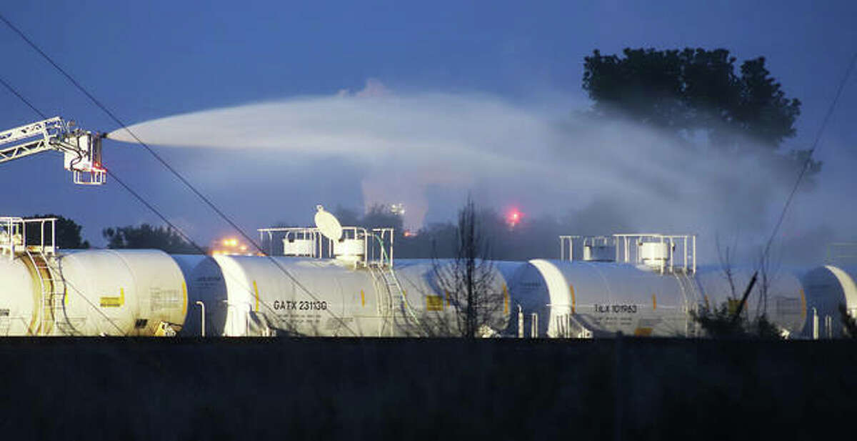 An unmanned aerial tower truck from the Wood River Fire Department sprays a water curtain over tank cars early Thursday on an isolated set of railroad tracks between Wood River and Hartford. The tank cars were reported to be venting spent sulfuric acid. The car with an open hatch, center, was the car of most concern along with three cars to the south of it.