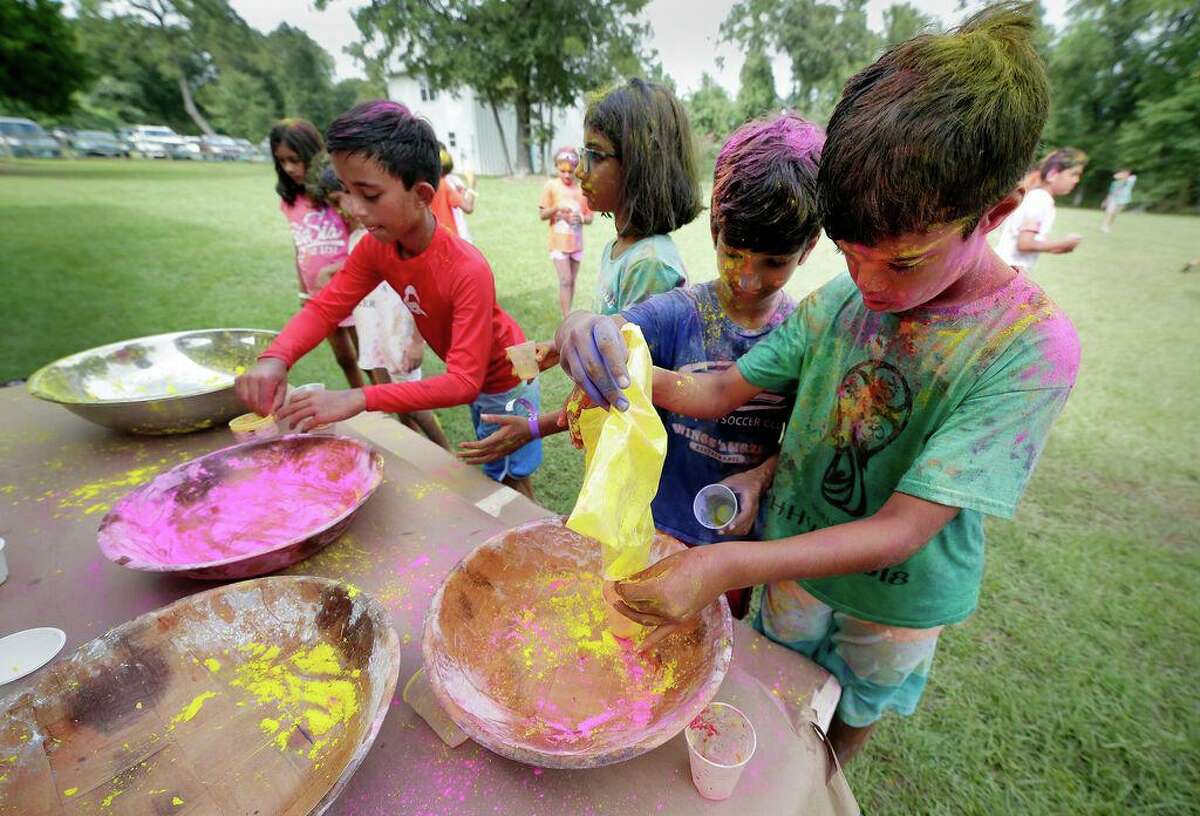 Elementary- and middle-school-aged campers, covered with colored powder, refill their cups during the Holi Festival celebration at the Hindu Heritage Youth Camp in 2019 at Camp Lantern Creek near Montgomery. Camp will resume in person this summer.