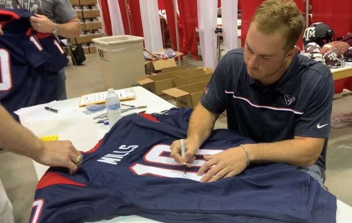 Rookie quarterback Davis Mills signs his Texans jersey at the TriStar show at NRG Arena in Houston on Saturday, June 5, 2021. 