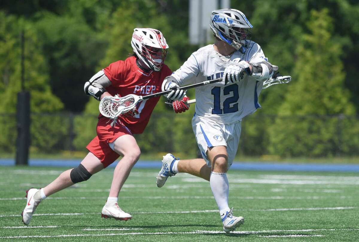 Darien’s Jamison Moore (12) carries the ball on offense while Fairfield Prep’s James McGrath (7) pursues during the Class L boys quarterfinals on Saturday.