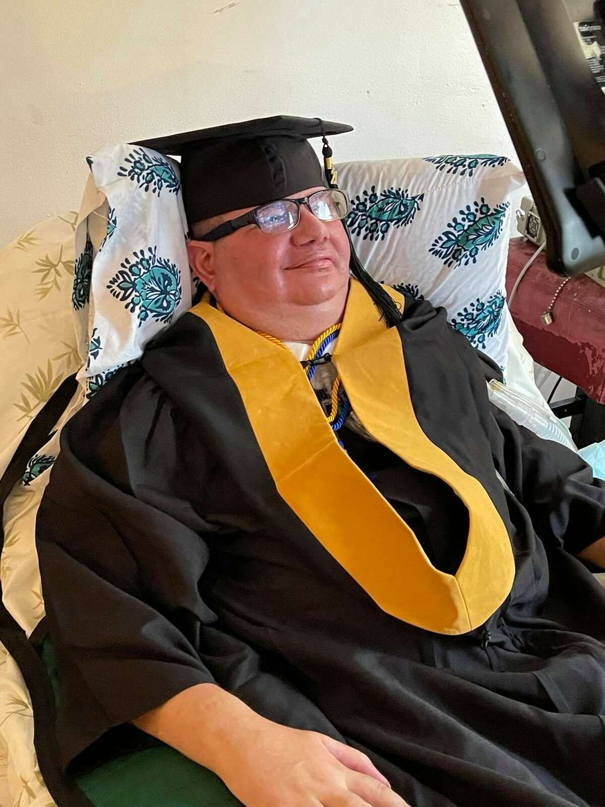 Eliseo Ilarraza wears his cap and gown for his online master's degree graduation ceremony from Our Lady of the Lake University.