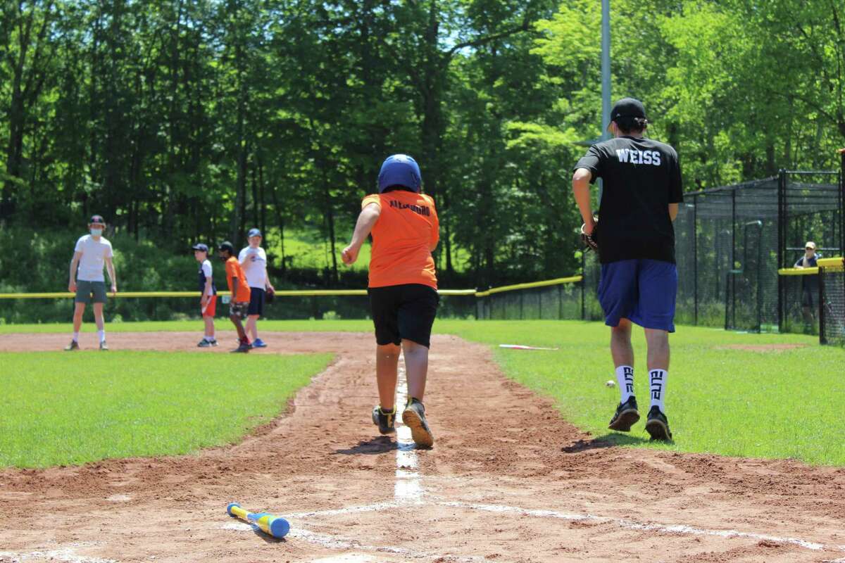 Holland Division player Alejandro darts for first base with his buddy, Danny Weiss, by his side. The seven-person team had its last game of the season on Saturday at Jensen Field in Ridgefield.