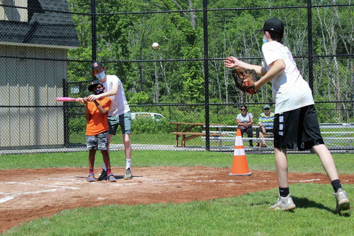 Holland Division player Atharv receives some help at bat from his buddy Milo Rosenzweig as Cormac Bellotti throws a pitch. The seven-person team had its last game of the season on Saturday at Jensen Field in Ridgefield.