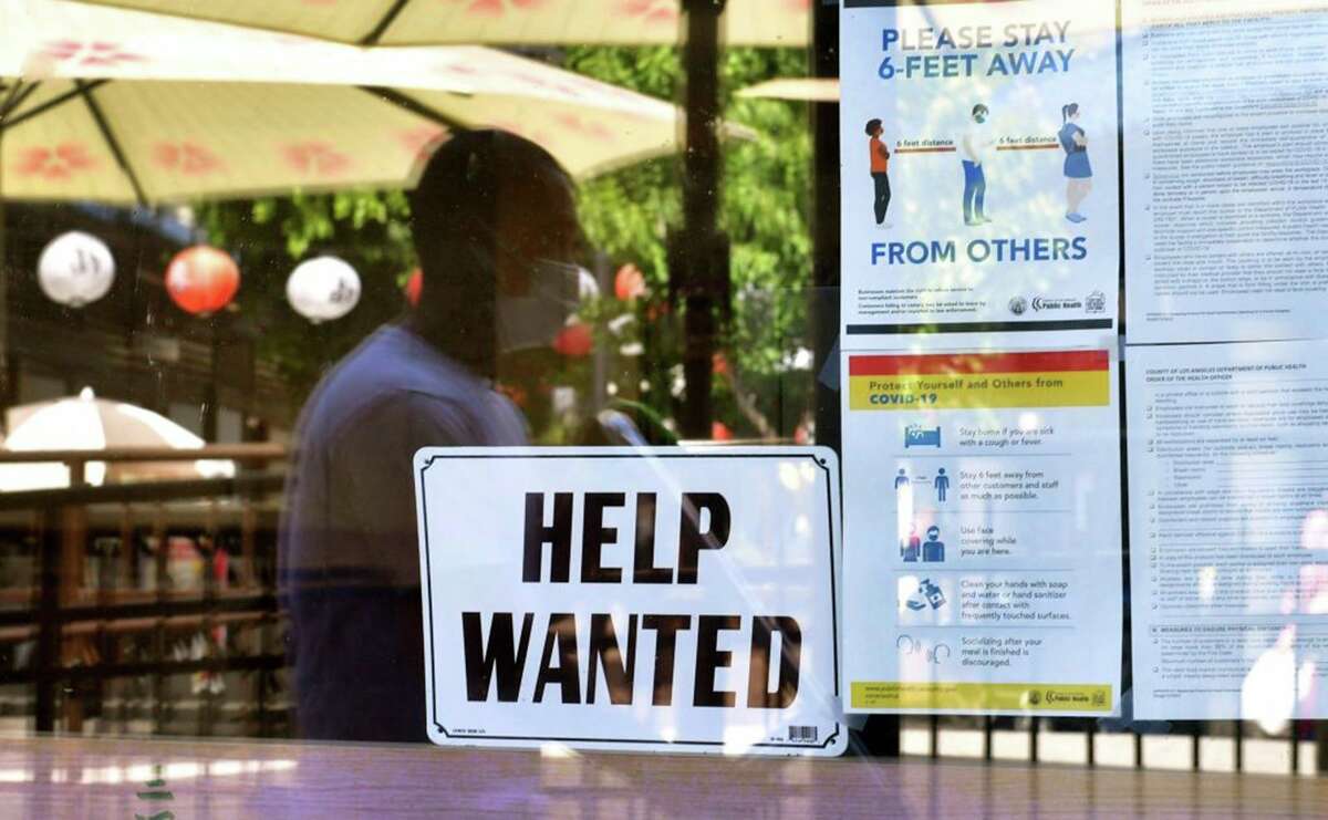 A "Help Wanted" sign is posted beside Coronavirus safety guidelines in front of a restaurant in Los Angeles, California on May 28, 2021. - Following over a year of restrictions due to the coronavirus pandemic, many jobs at restaurants, retail stores and bars remain unfilled, despite California's high unemployment rate, causing some owners to fear they will not be able to fully reopen by the June 15th date California has given for a full reopening of the economy. (Frederic J. Brown/AFP via Getty Images/TNS)