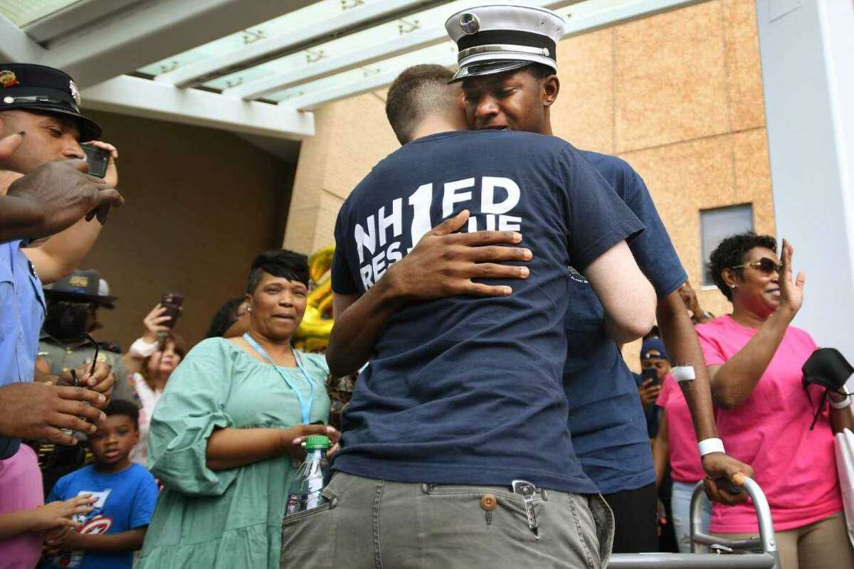 New Haven fire Lt. Samod “Nuke” Rankins, facing, hugs fellow firefighter James Kiley upon his release from the Bridgeport Hospital burn unit in Bridgeport on May 23, 2021.