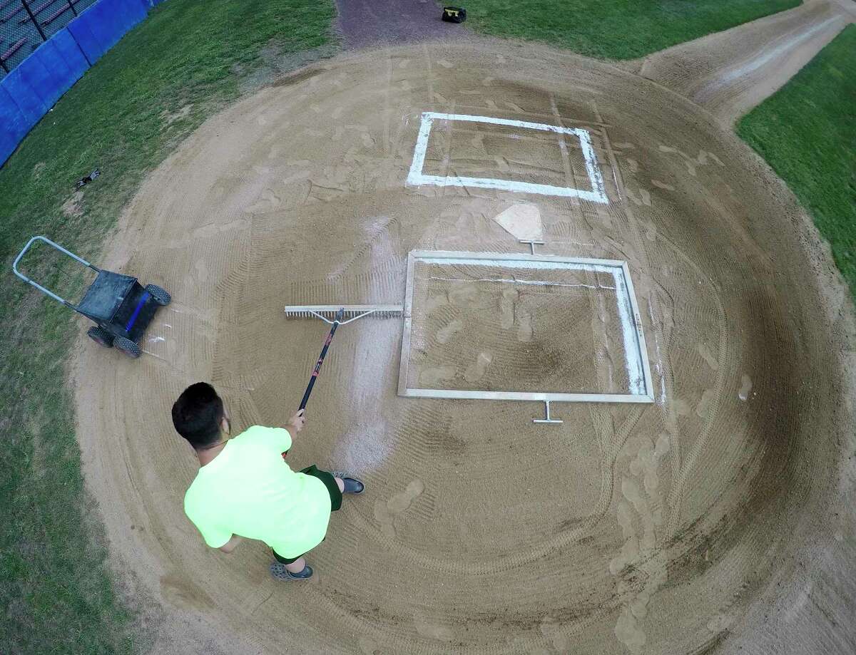 Mike Pinto, an employee with the City of Stamford Parks and Recreation Department layouts and stripes the batters box at Cubeta Stadium in preparation for games on July 28, 2020 in the Stamford Babe Ruth Baseball League in Stamford, Connecticut. Pinto was be helped by fellow employee Gamalier Feliciano as the two endured sweltering heat while maintaining one of a couple of dozen city fields around Stamford.