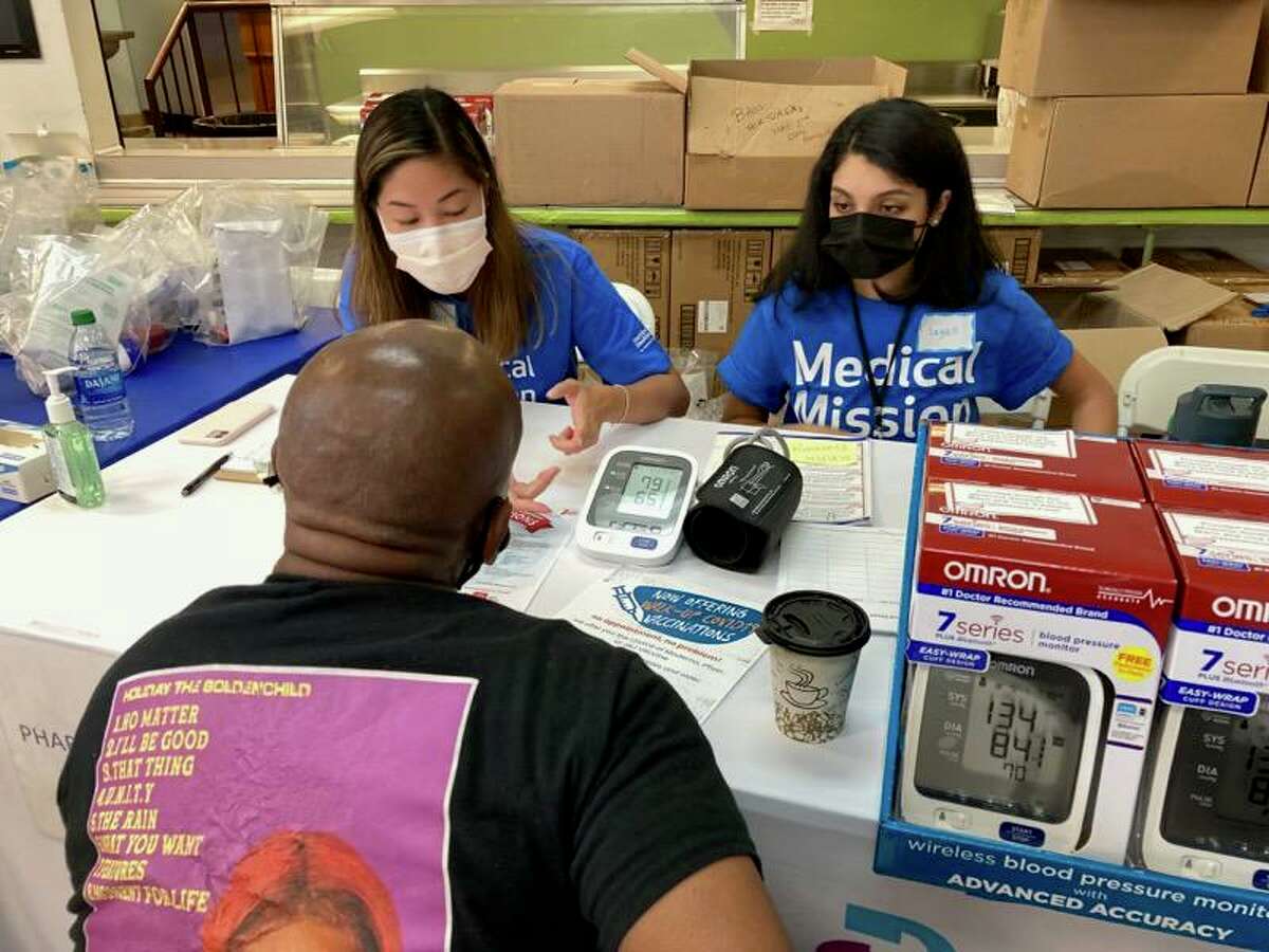 St. Vincent’s Medical Center pharmacy residents Anne Lin and Sayali Oak help patient Juan Garcia at St. Vincent's Medical Center's sixth “Medical Mission at Home,” which took place June 5, 2021 at Thomas Merton House in Bridgeport.