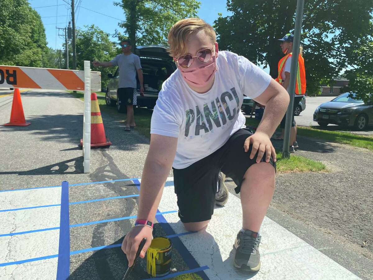 Luke Lombardi, 15, helping to repaint a crosswalk in Pride colors.