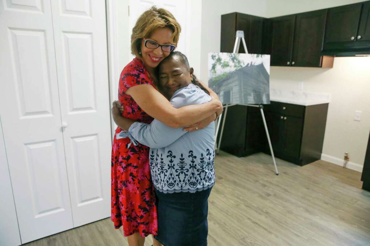 San Antonio City District 5 Councilwoman Shirley Gonzales, left, hugs Laura Martinez, 61, after handing her the keys to her house Monday. Martinez’s modified shotgun house, nearly 100 years old, was in disrepair and was renovated through a city program.