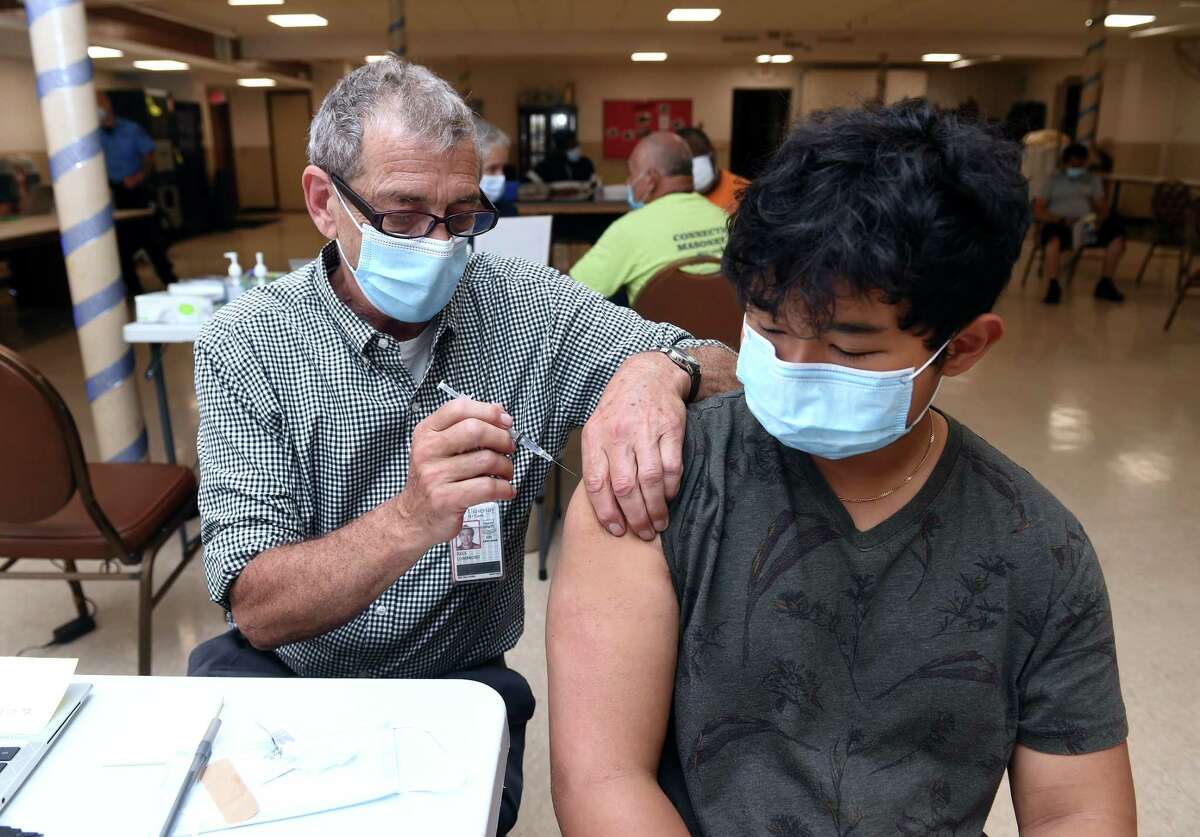 Dr. Paul Lombroso (left) gives the first shot of a Pfizer COVID-19 vaccine to Angel Irigoyen, 15, of Bethany during a vaccine clinic organized by the Beulah Heights First Pentecostal Church, URU The Right To Be, Inc. and Yale New Haven Hospital in the basement of the Beulah First Heights Pentecostal Church in New Haven on June 8, 2021. The clinic will be back at this location in three weeks for the second dose of the vaccine.