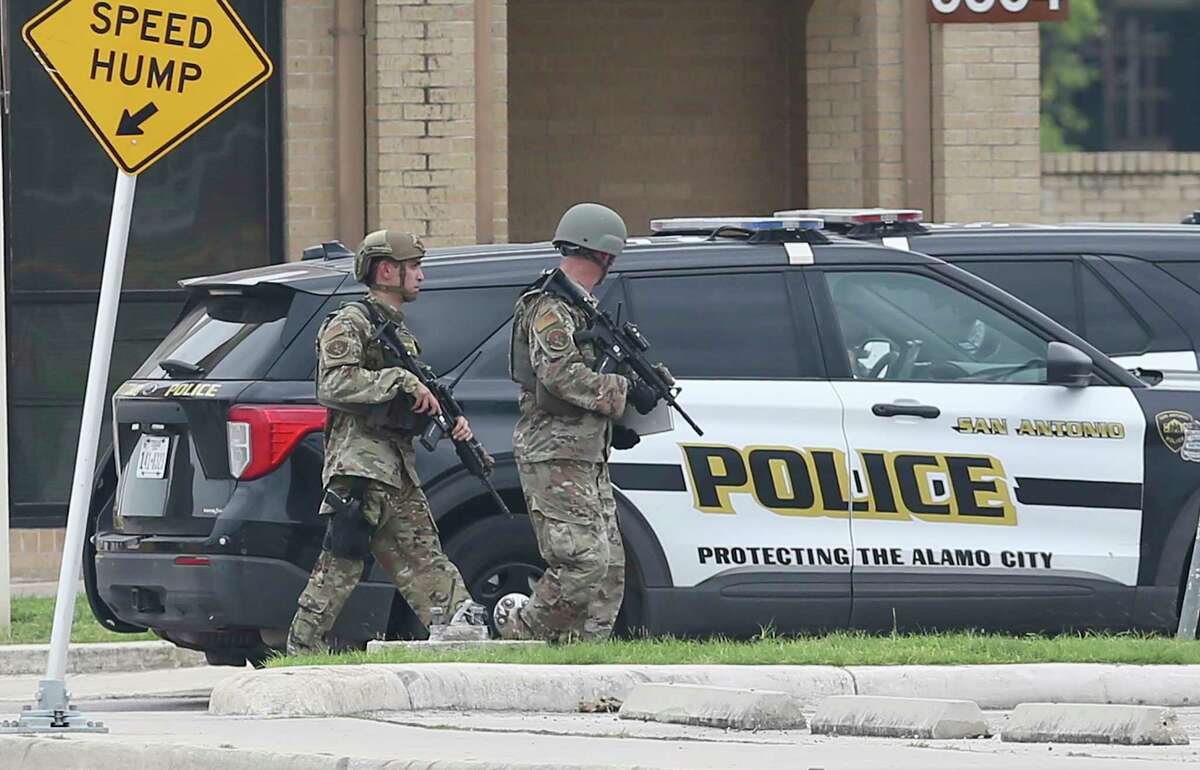 Lackland security personnel are seen carrying weapons as they walk past a SAPD police vehicle as JBSA-Lackland was on lockdown on Wednesday, June 9, 2021 on reports of an active shooting situation. Military Police, San Antonio Police Department and Texas State Troopers could be seen at the Valley Hi entrance of the base.