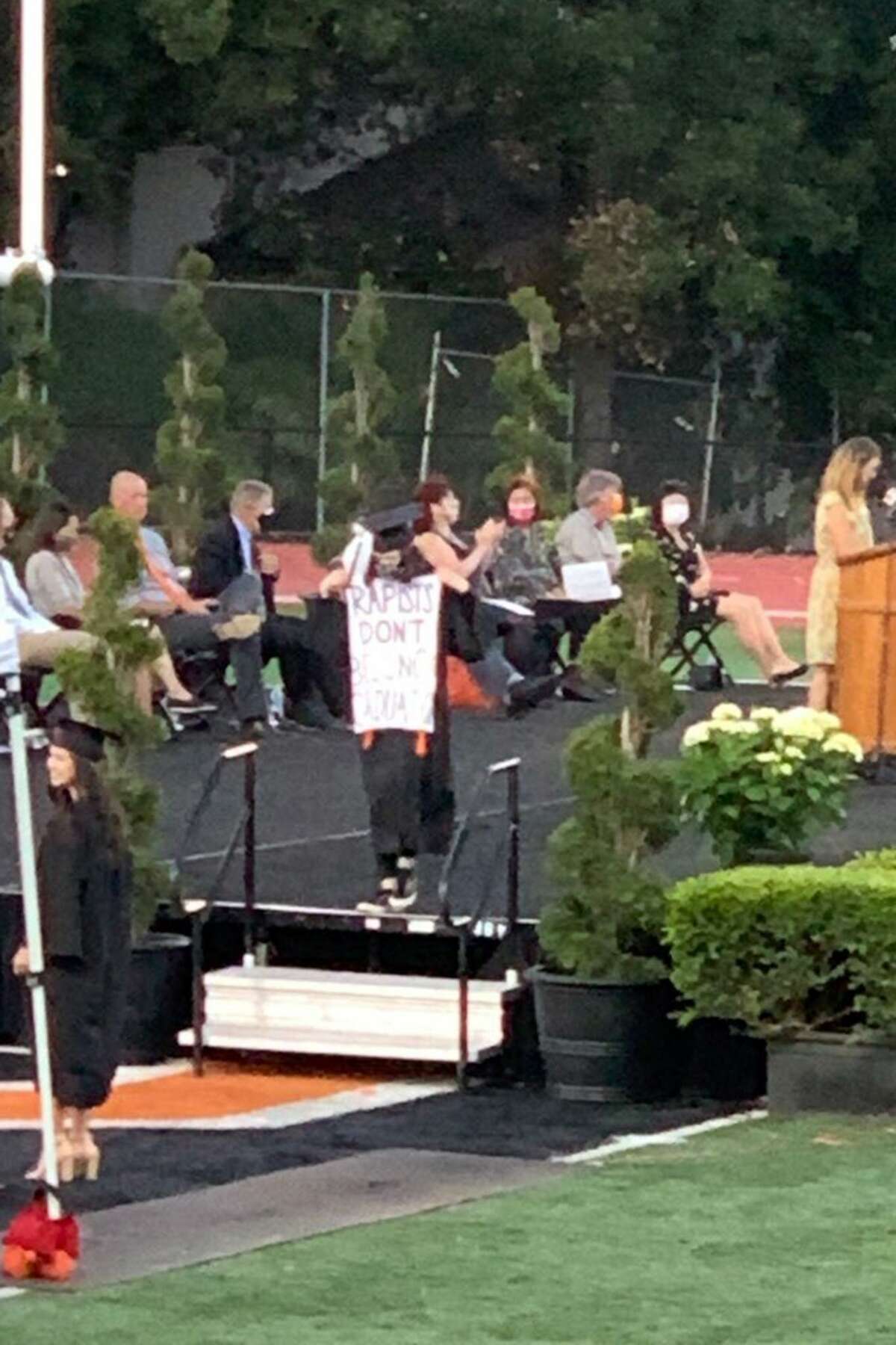 Los Gatos High student graduates holding sign 'Rapists don't belong