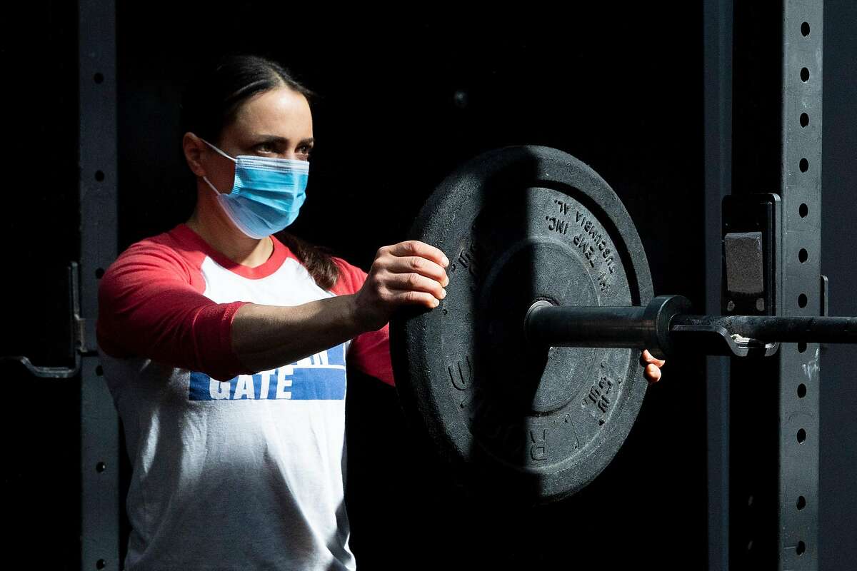 Crossfit Golden Gate gym owner Danielle Rabkin wears a mask while arranging weights before working out at her gym in San Francisco, Calif. Tuesday, October 13, 2020. 