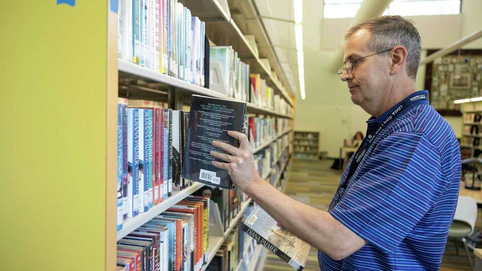 Mark Haywood, adult services librarian, organizes books on shelves at the Kingwood library, Wednesday, June 9, 2021, in Kingwood. Libraries through the Harris County Public Library system were closed due to the COVID-19 pandemic but recently opened again at 75% of buildings' maximum capacity after the county upgraded the COVID-19 threat level.