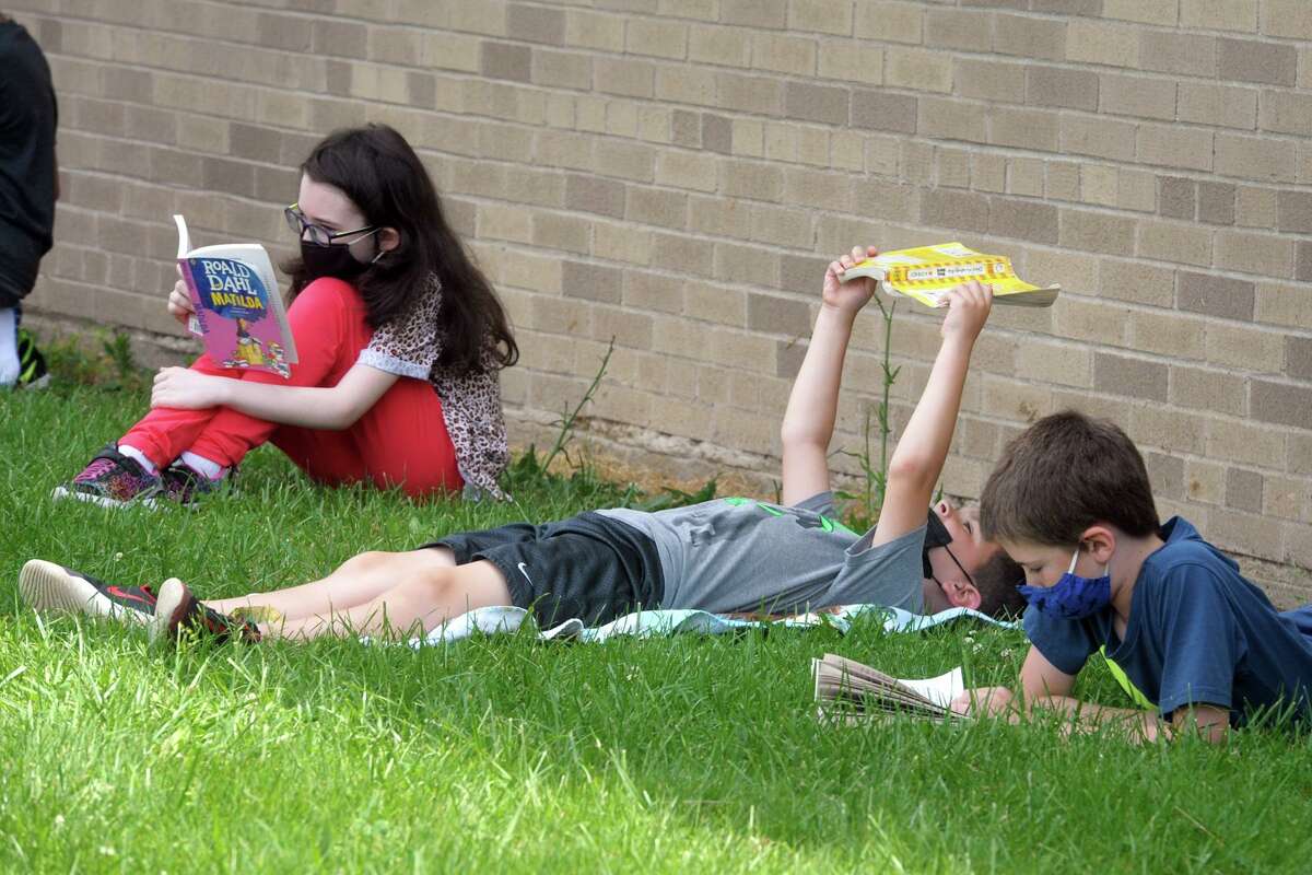 Students read in the shade Long Hill School in Shelton on Tuesday.