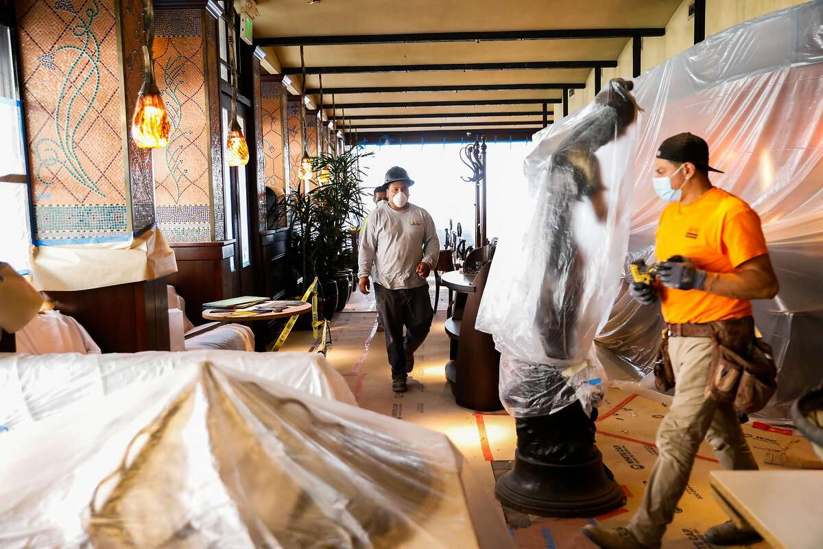 Workers walk through Boulevard restaurant while doing renovations to install new fabric designs and repaint before their reopening later this summer on Friday, May 28, 2021 in San Francisco, California.