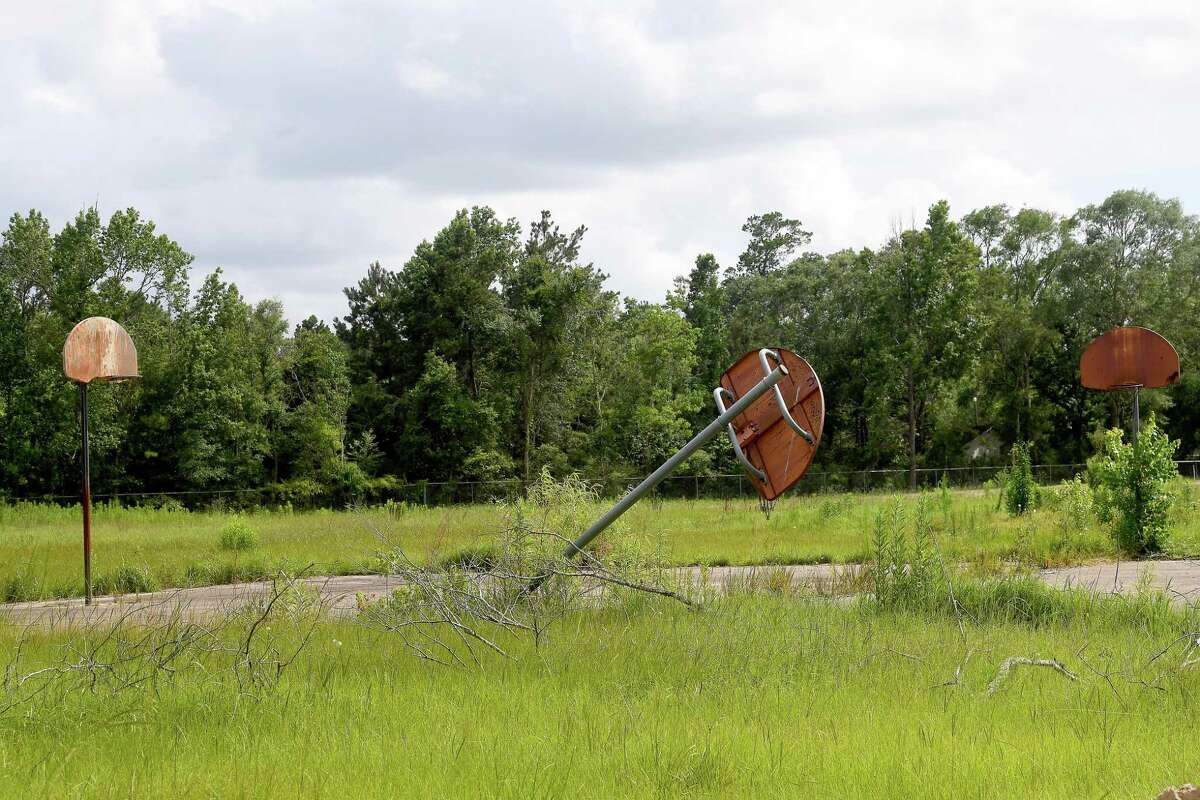 Weathered basketball hoops are all thhat rremain of the playground that was at Vidor Middle School. Members of Vidor ISD's school board and representatives from G&G Construction gather for a groundbreaking ceremony on the long-awaited new Vidor Middle School Thursday. Students and teachers have been working out of portables since the school flooded during Harvey in 2017. Photo made Thursday, June 10, 2021 Kim Brent/The Enterprise