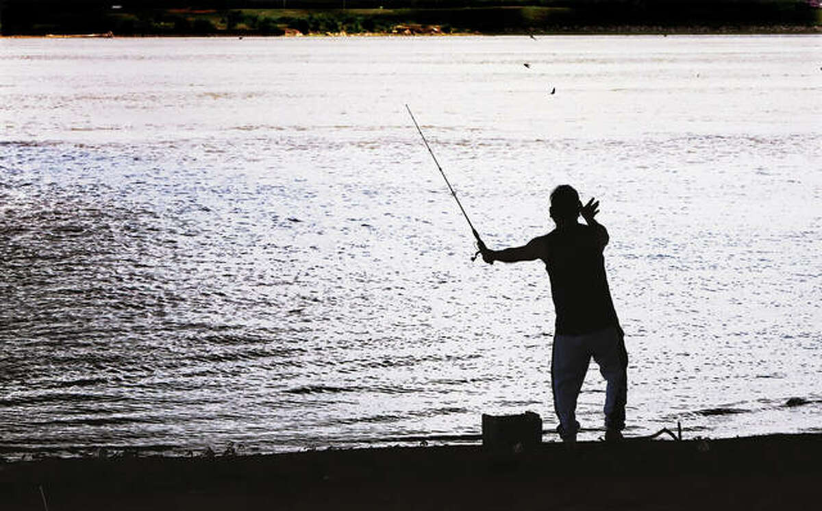 A fisherman is silhouetted Monday by the bright Mississippi River as he casts his line near the Clark Bridge in Alton.