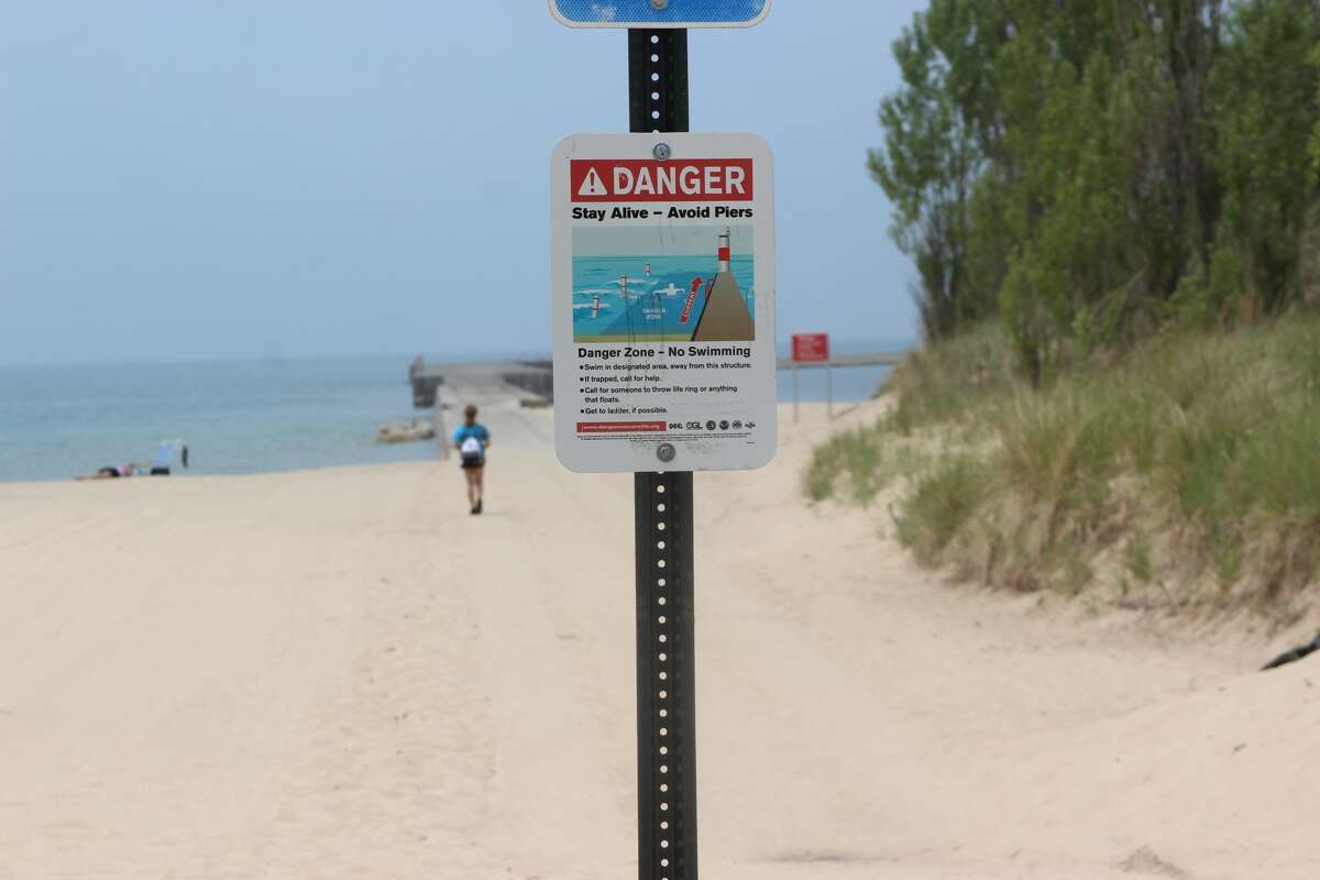 A sign at Manistee's First Street Beach warns visitors to avoid swimming near piers.
