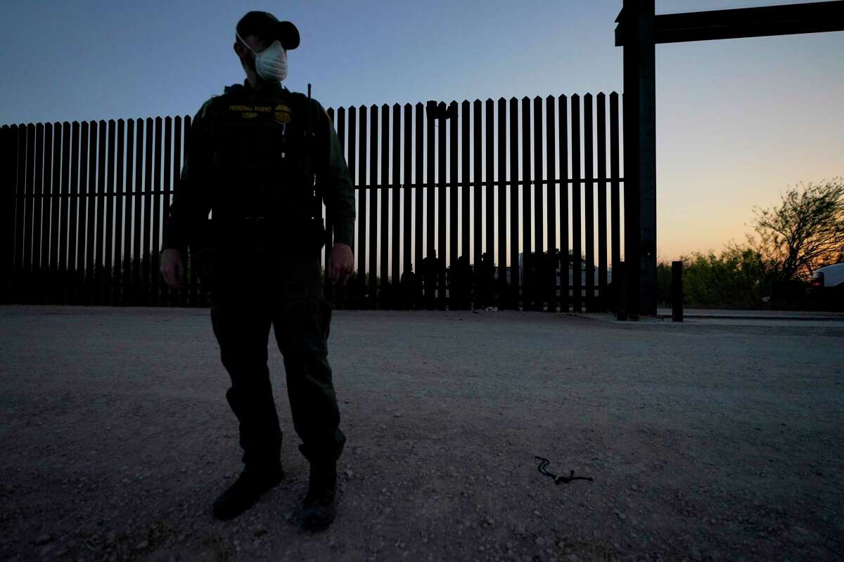 En esta fotografía de archivo del 21 de marzo de 2021, un agente de la Oficina de Aduanas y Protección Fronteriza monta guardia cerca de una puerta en el muro en la frontera entre México y Estados Unidos durante un operativo de detención de migrantes, en Abram-Perezville, Texas.