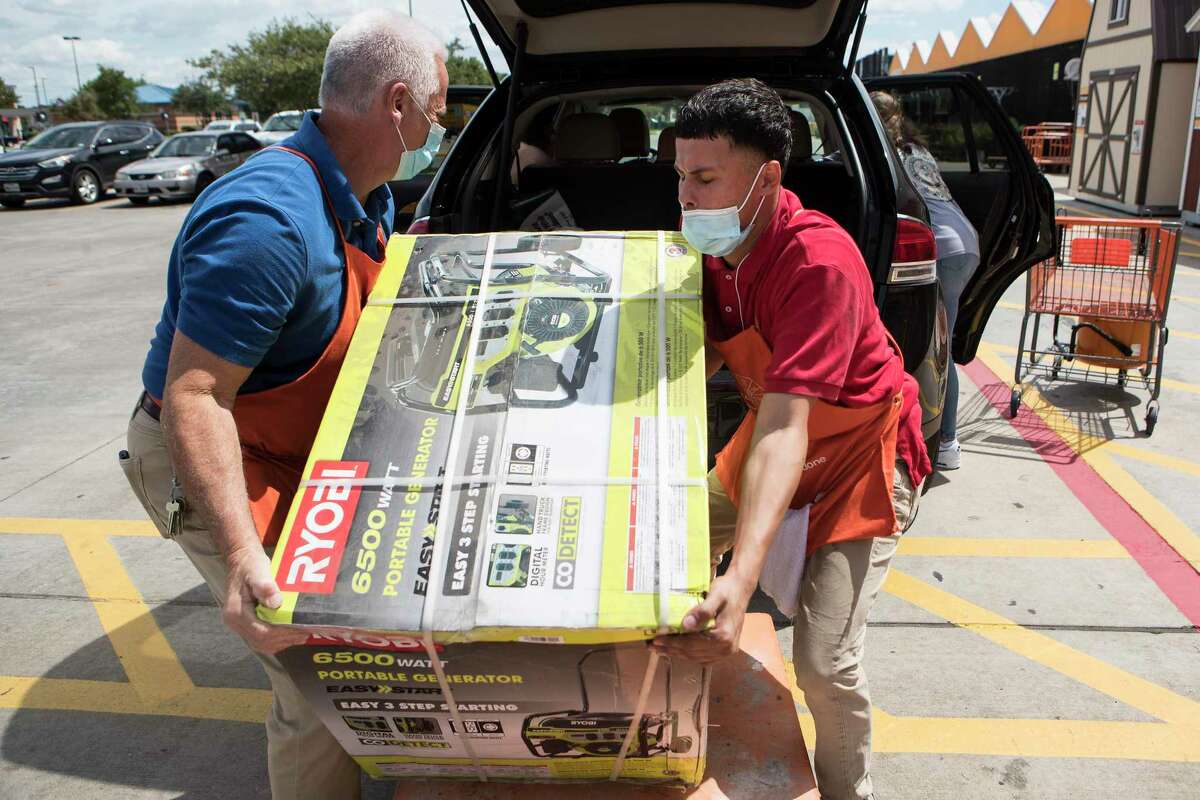 John Prekosovich, left, and Joel Canales loads a portable generator into customer's vehicle at a Home Depot store while preparing for the possible landfall of Hurricane Laura on Tuesday, Aug. 25, 2020 in Houston.