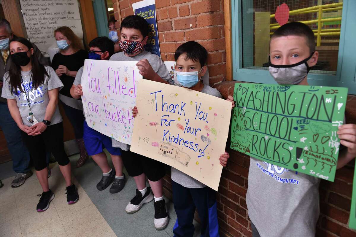 From left, Christina Lorenti listens to speakers as her fourth-grade students Christopher Schlauder, Nathan Silvia, Jose Rangel and Jayce Peluso hold signs of appreciation during a press conference announcing $24 million in funding toward the cost of a new Washington Elementary School in West Haven on June 14, 2021.