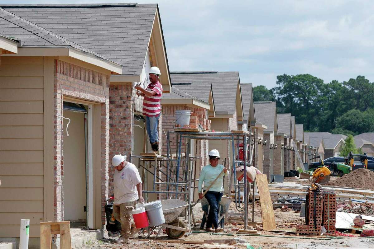 Construction workers lay bricks on the exteriors of new houses by LGI Homes along Lost Lantern Drive in a new section of the Bauer Landing sub-division Thursday, June 3, 2021 in Hockley, TX.