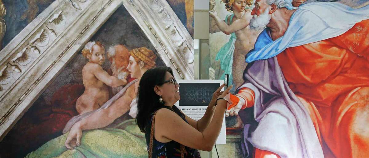 Maricela Espinoza-Garcia documents the artwork during a preview for “Michelangelo’s Sistine Chapel” at Lambermont Events.