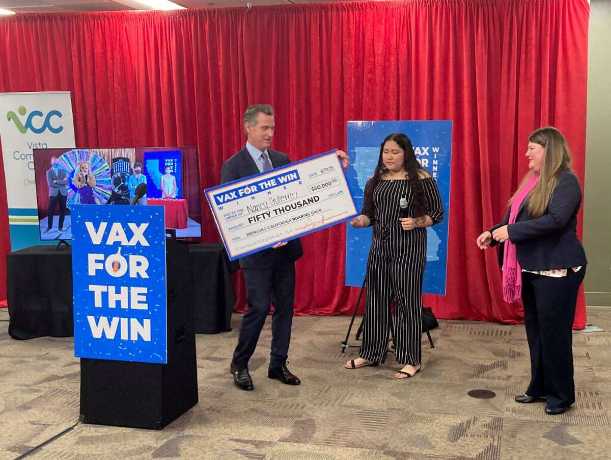 Gov. Gavin Newsom presents a check to Nancy Gutierrez, the winner of $50K lottery for getting vaccinated as Assemblywoman Tasha Boerner Horvath, right looks on in San Diego, Calif. on Friday, June 11, 2021.