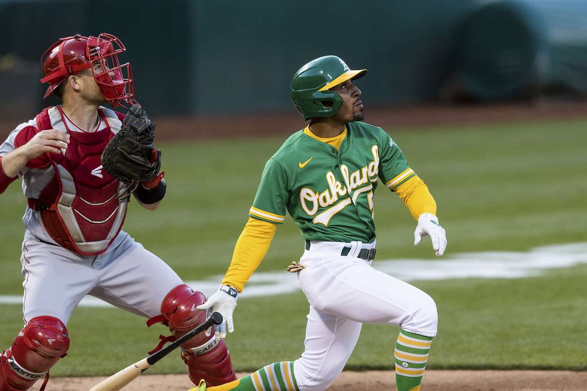 Oakland Athletics' Tony Kemp, right, hits an RBI-triple in front of Los Angeles Angels catcher Max Stassi during the third inning of a baseball game in Oakland, Calif., Monday, June 14, 2021. (AP Photo/John Hefti)