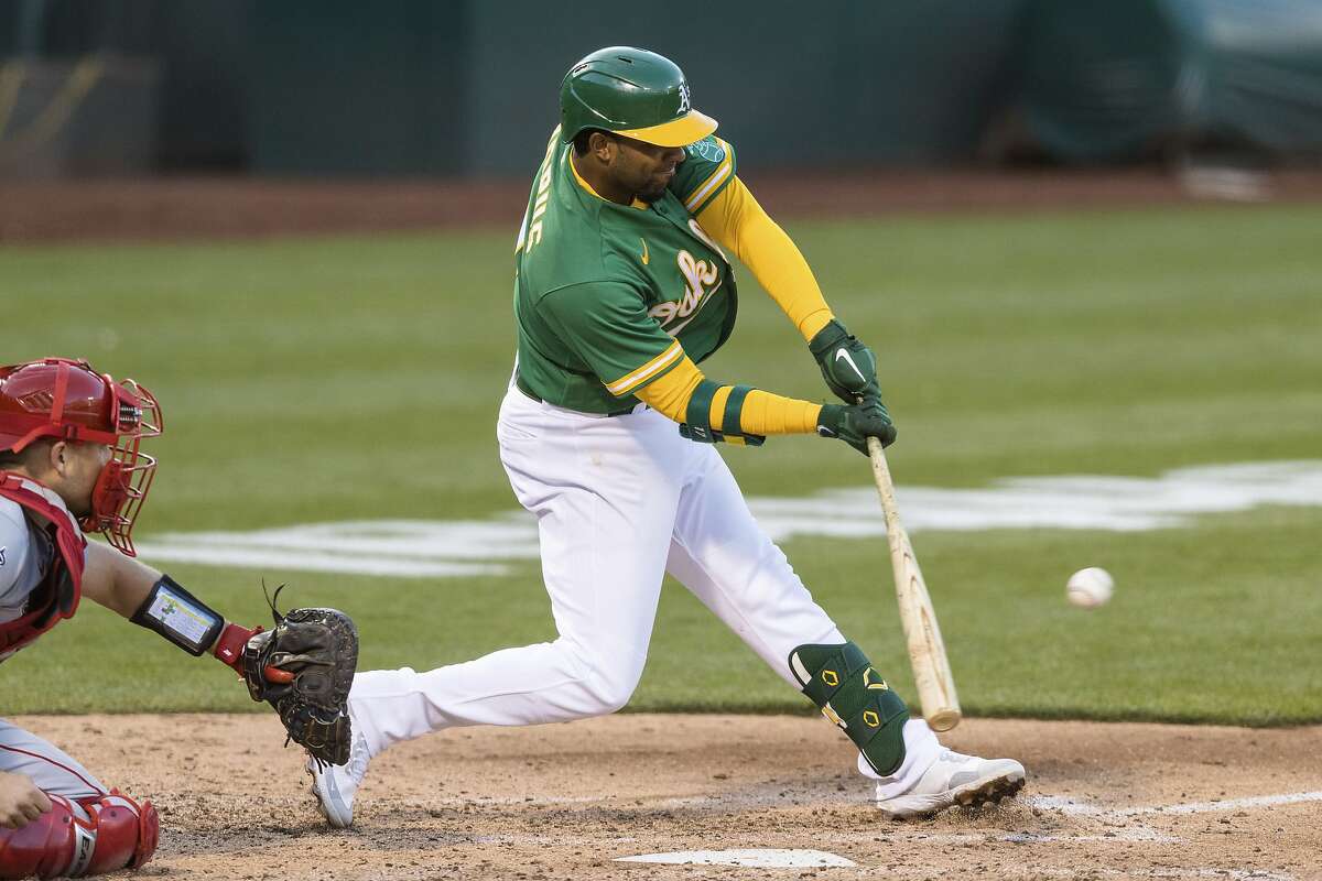 Oakland Athletics' Elvis Andrus, right, hits an RBI single in front of Los Angeles Angels catcher Max Stassi during the third inning of a baseball game in Oakland, Calif., Monday, June 14, 2021. (AP Photo/John Hefti)